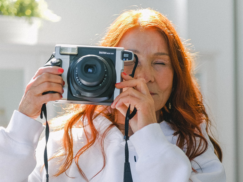 Femme tenant un appareil photo devant son visage