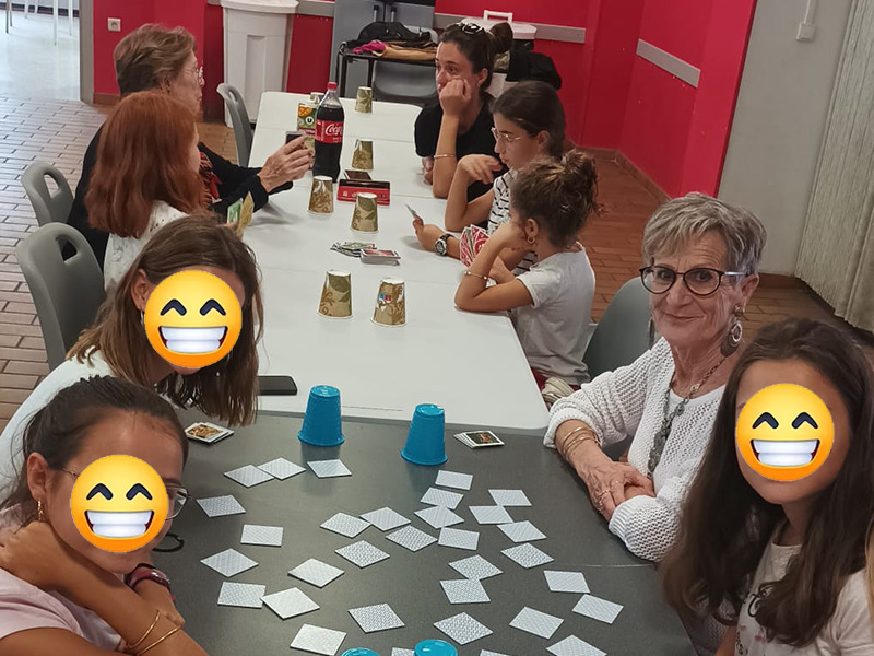 Enfants, adultes et seniors jouent aux jeux de société autour d'une table.